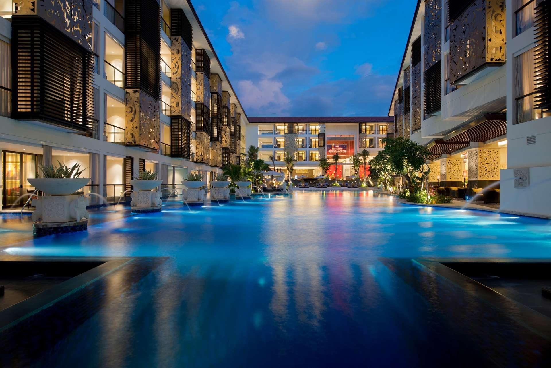 The Trans Resort Bali pool courtyard illuminated at dusk